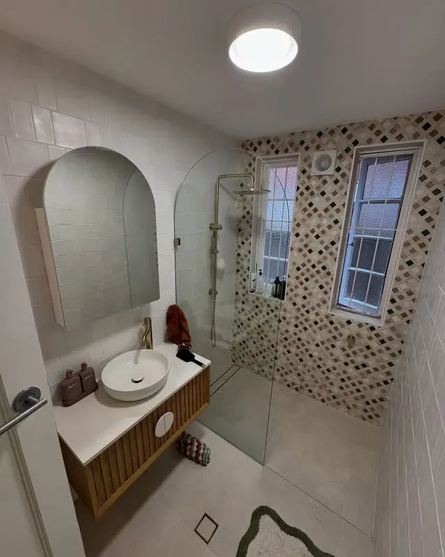 Rose Bay bathroom with arched mirror, wall-hung vanity and brass-toned tapware