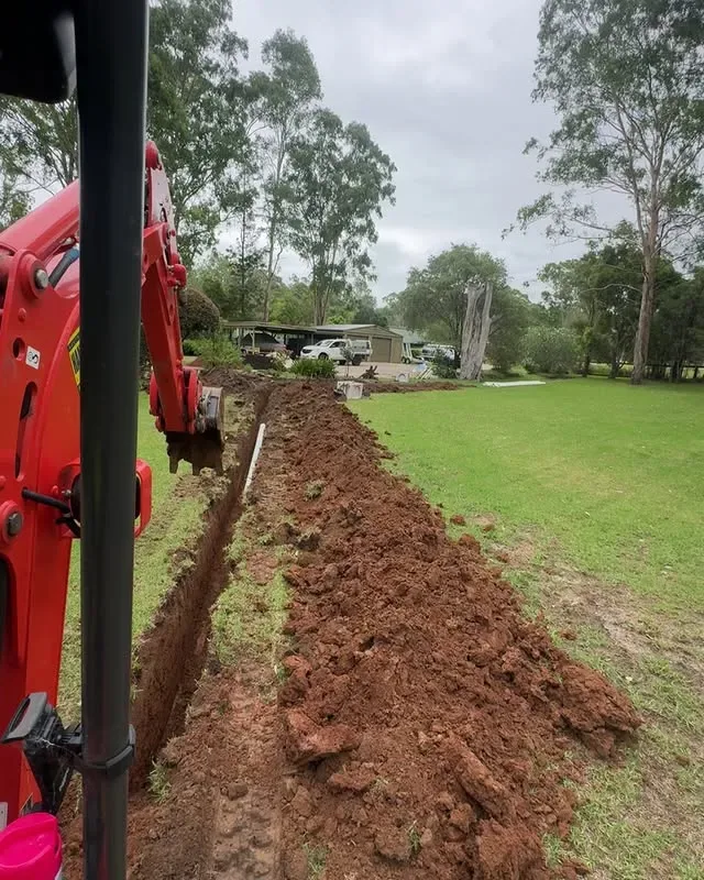 Excavator beside a drainage trench running along a Wilberforce lawn
